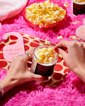 Bougie Popcorn & Caramel « Netflix & chill » allumée près d'un bol de popcorn