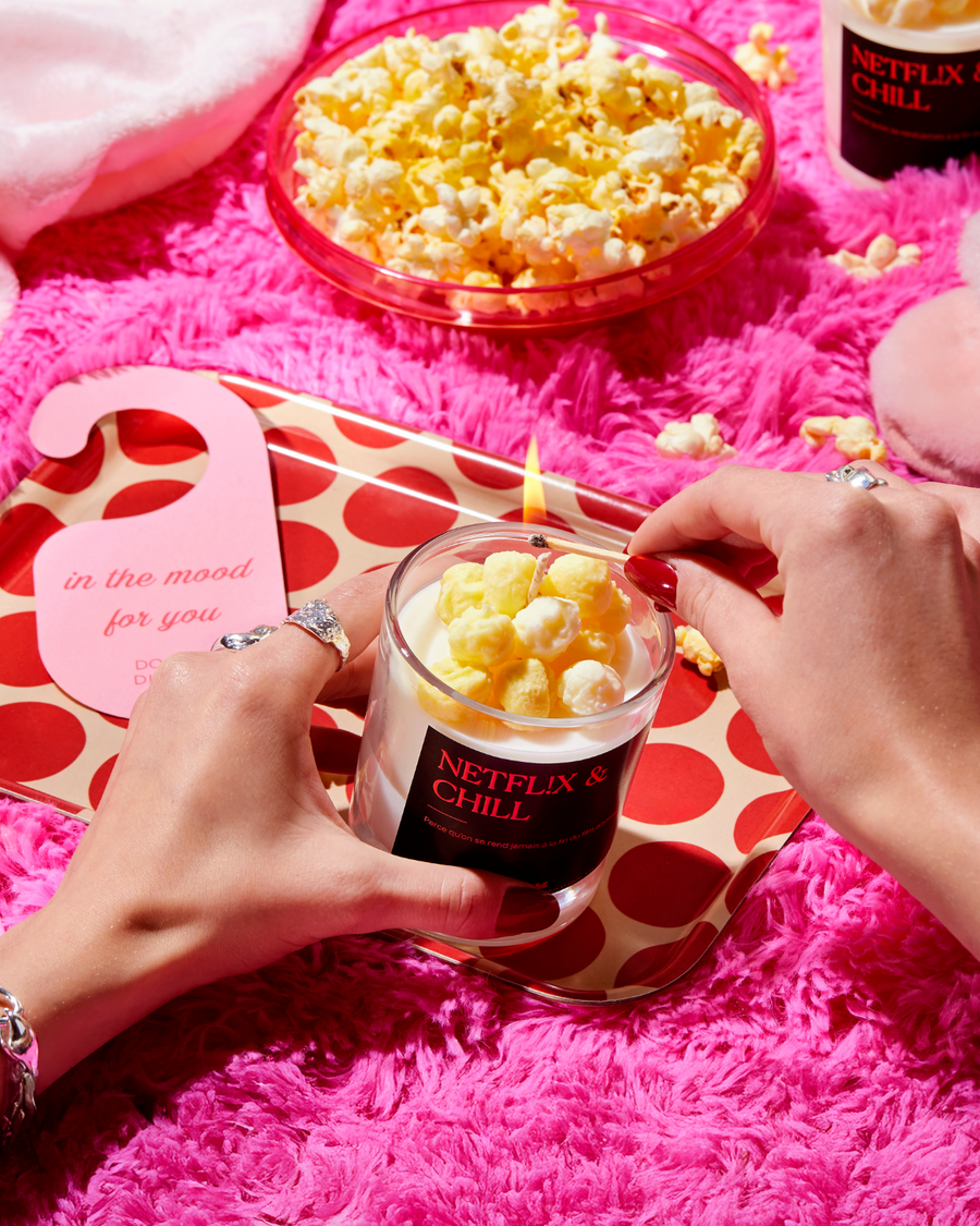Bougie Popcorn & Caramel « Netflix & chill » allumée près d'un bol de popcorn